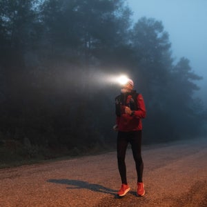Man running a backyard ultra with headlamp in dark foggy weather