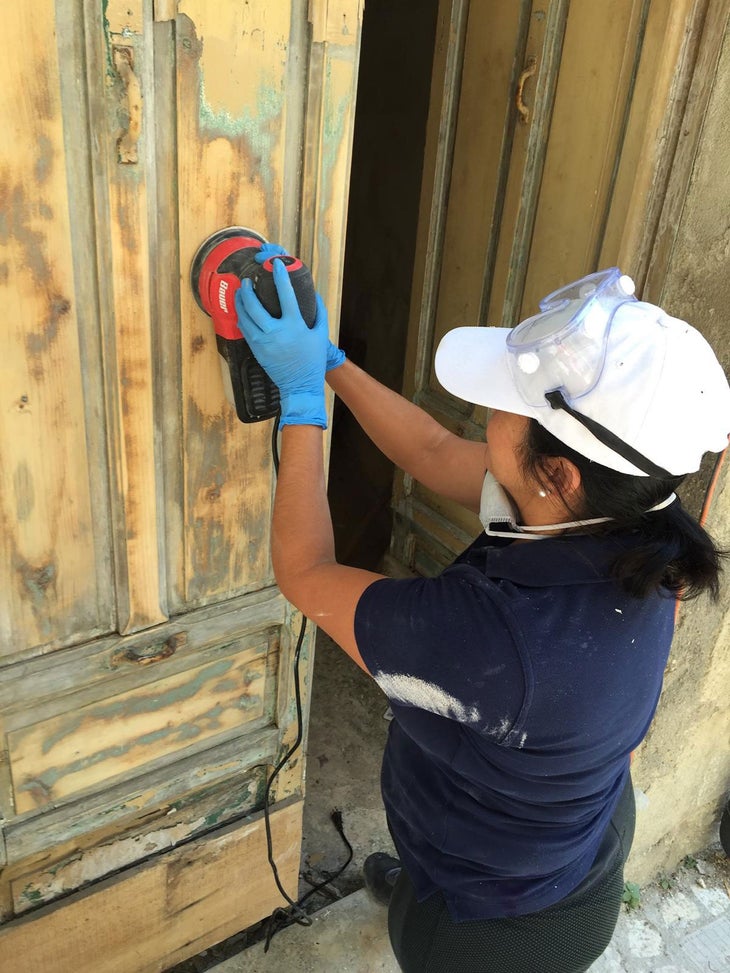 Rubia Daniels sanding down the wood of her front door