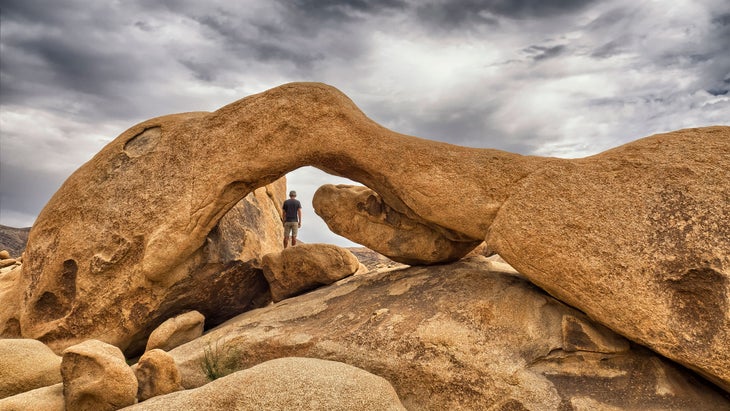 Man Standing at Arch Rock at Joshua Tree National Park