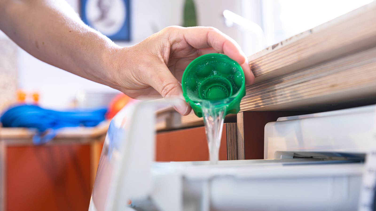 Pouring Nikwax detergent into a washing machine.