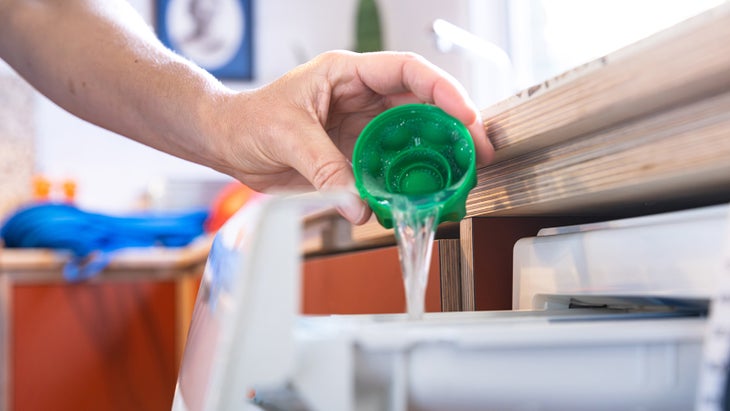 Pouring Nikwax detergent into a washing machine.