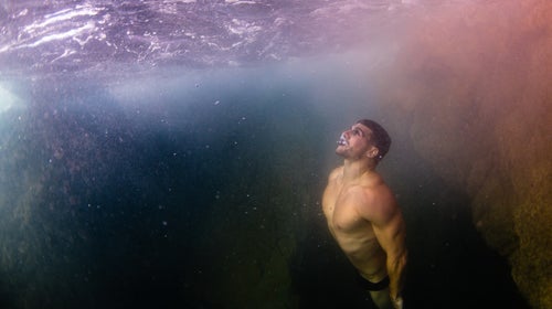 A white male diver swims to the surface after a breath hold