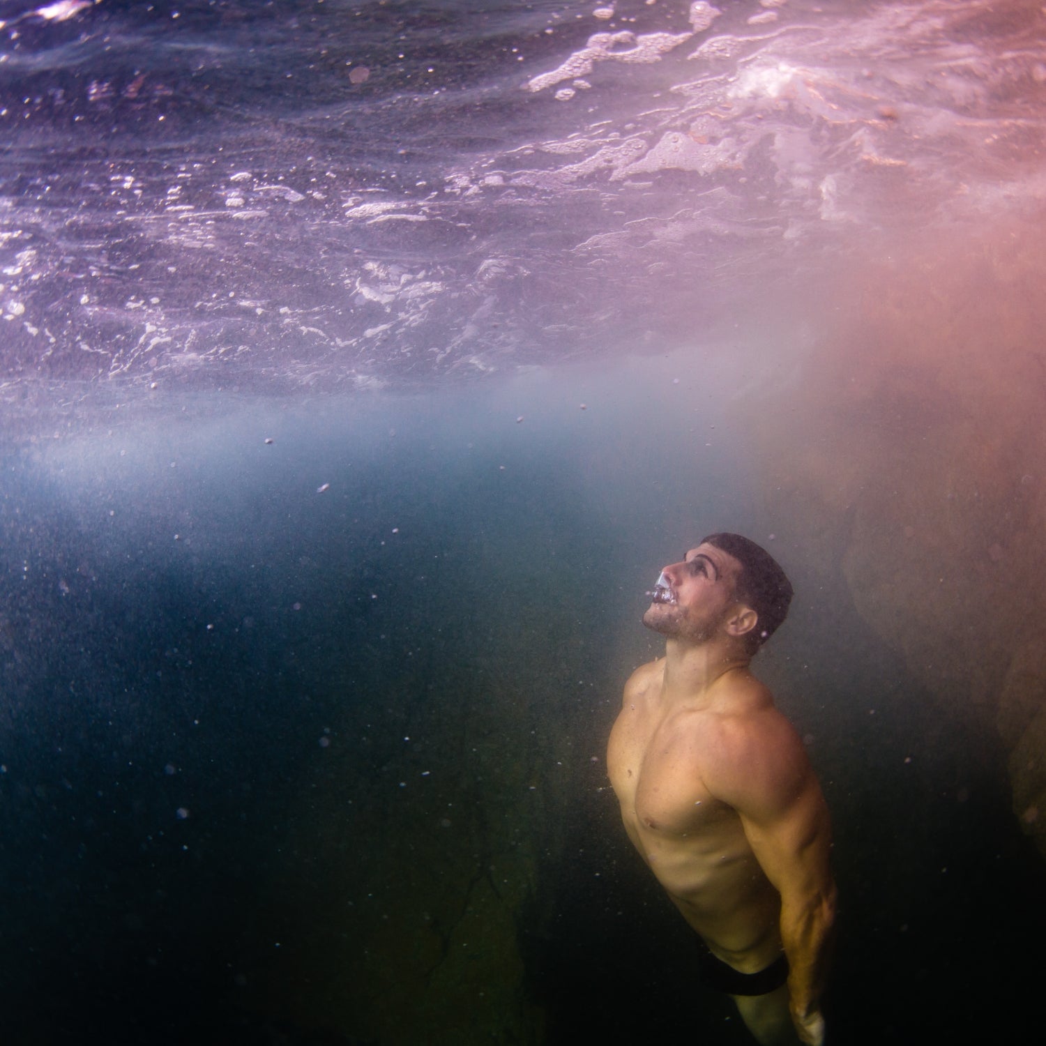 A white male diver swims to the surface after a breath hold