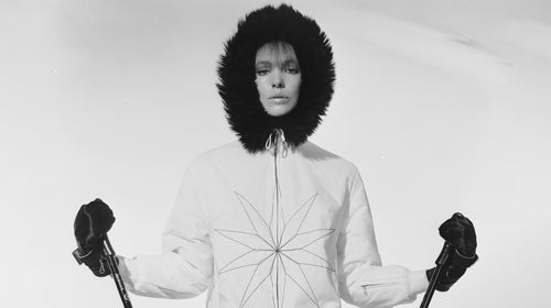 September 1965: A woman in a Gordon Lowe white skiing jacket with a star motif and a black fur hood prepares to set off down the piste