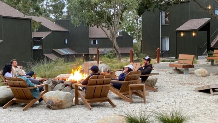 A group of people sit in Adirondack chairs around the central fire pit at Northern California’s Lodge at Marconi.