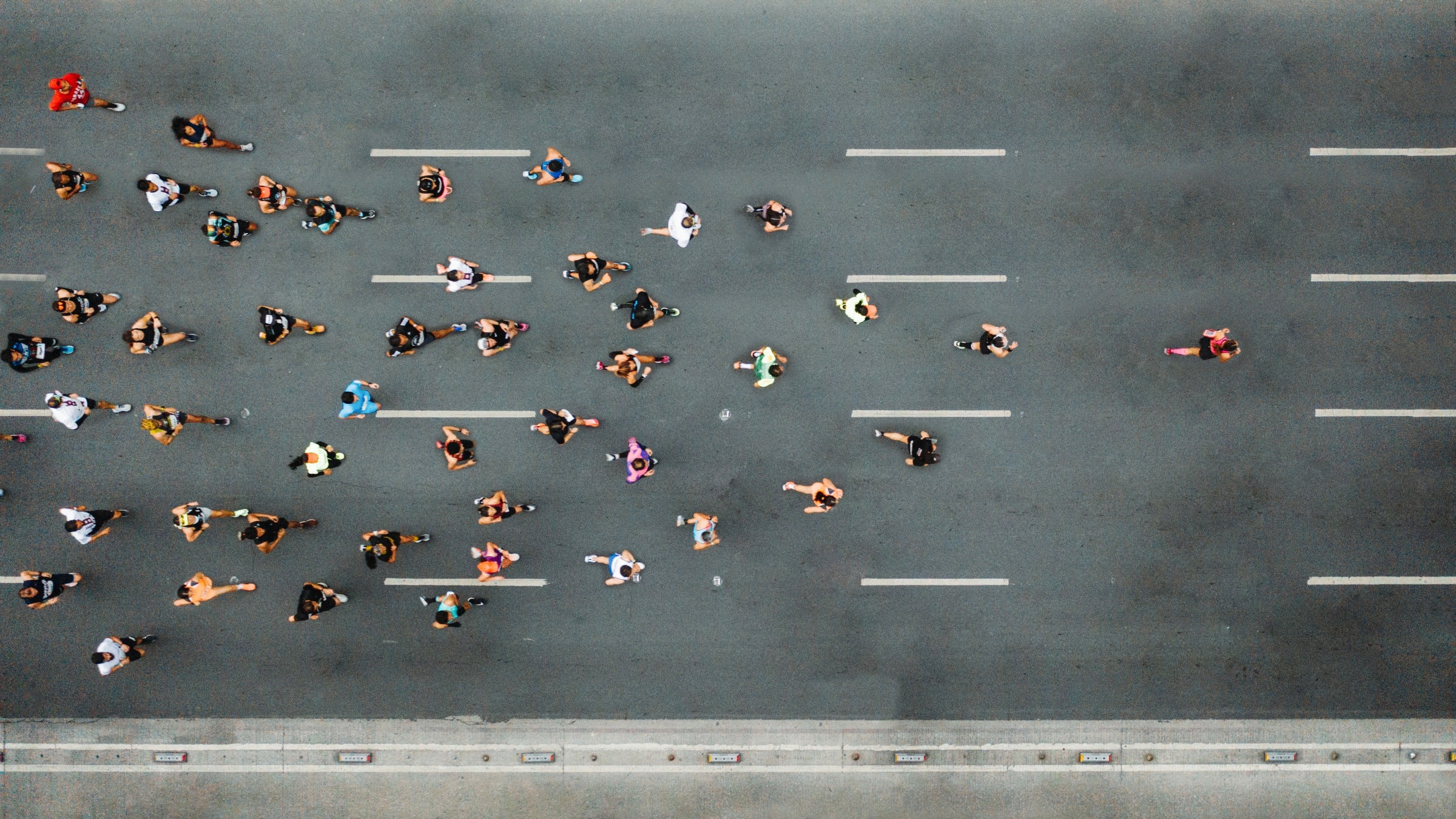 A group of marathon runners racing in the street photographed from above.