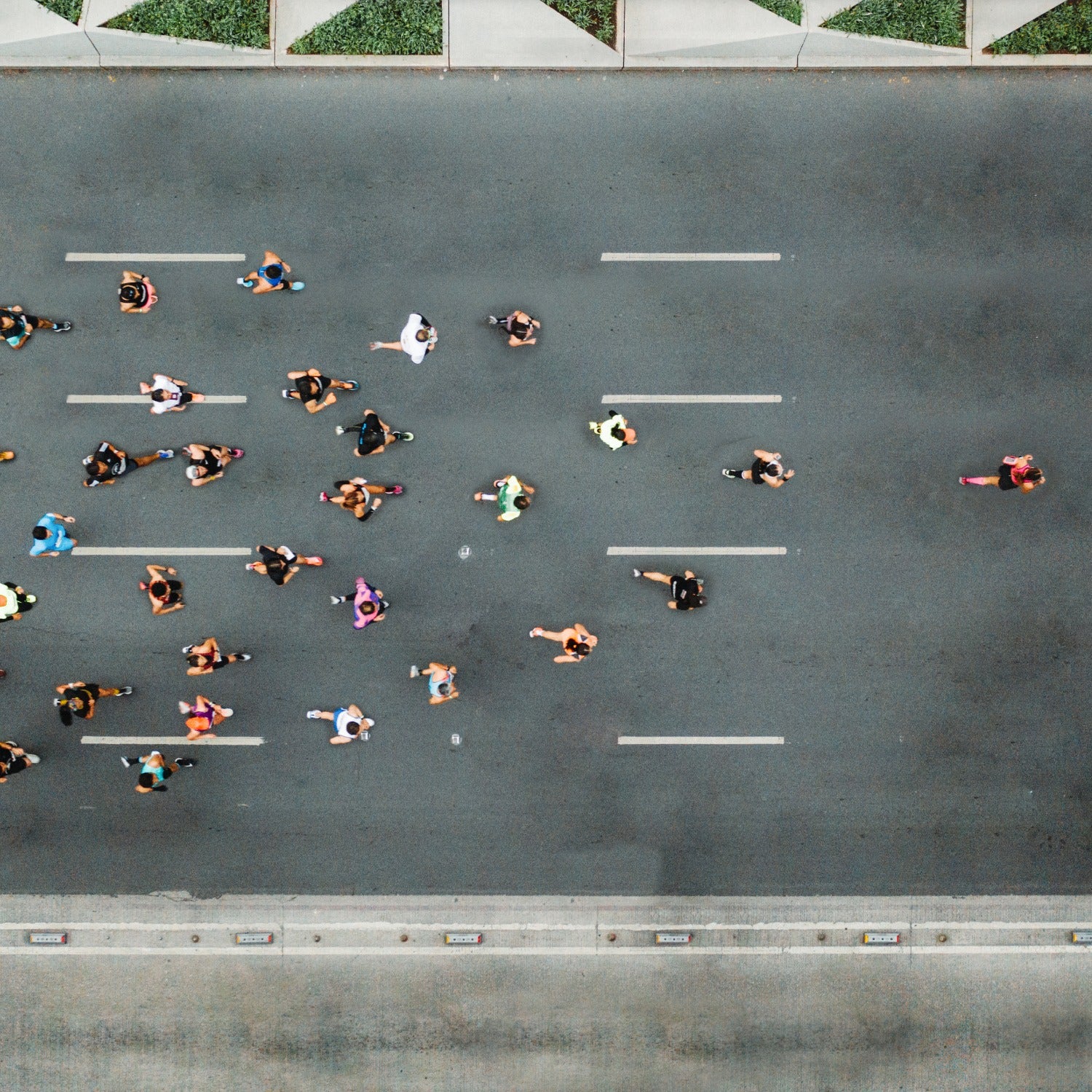 A group of marathon runners racing in the street photographed from above.