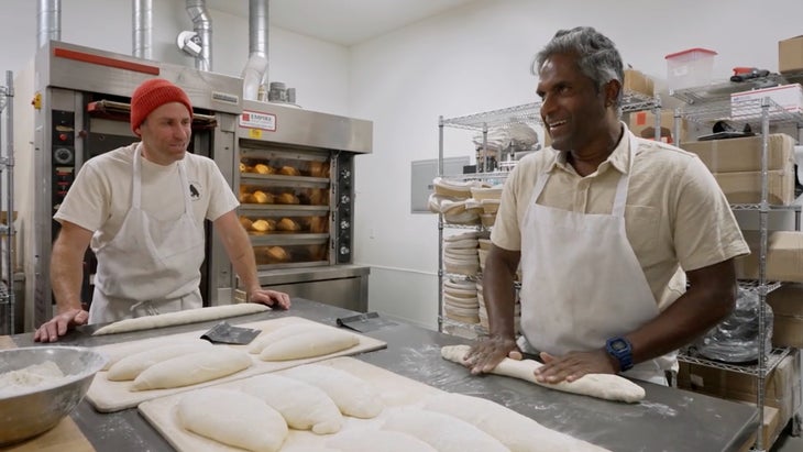 two men rolling out bread dough