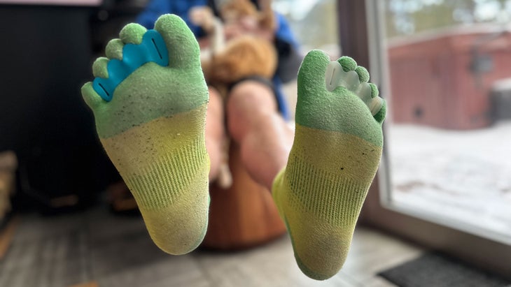 man wearing toe socks sitting back with cat