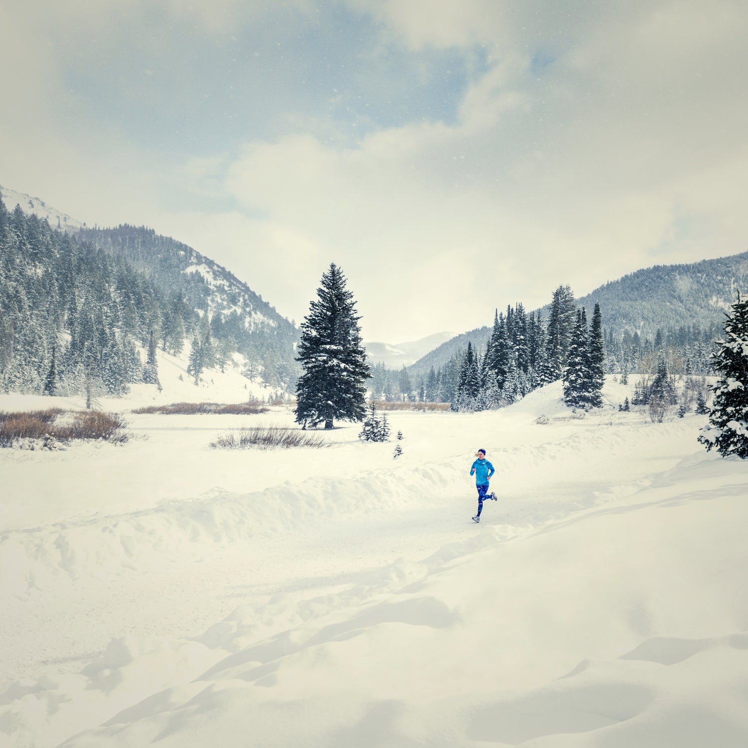 A caucasian woman runs down a plowed road in snowy landscape