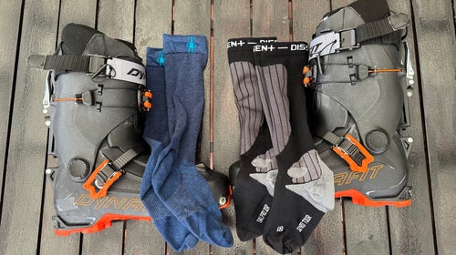 Closeup of wool socks and synthetic socks next to ski boots on table