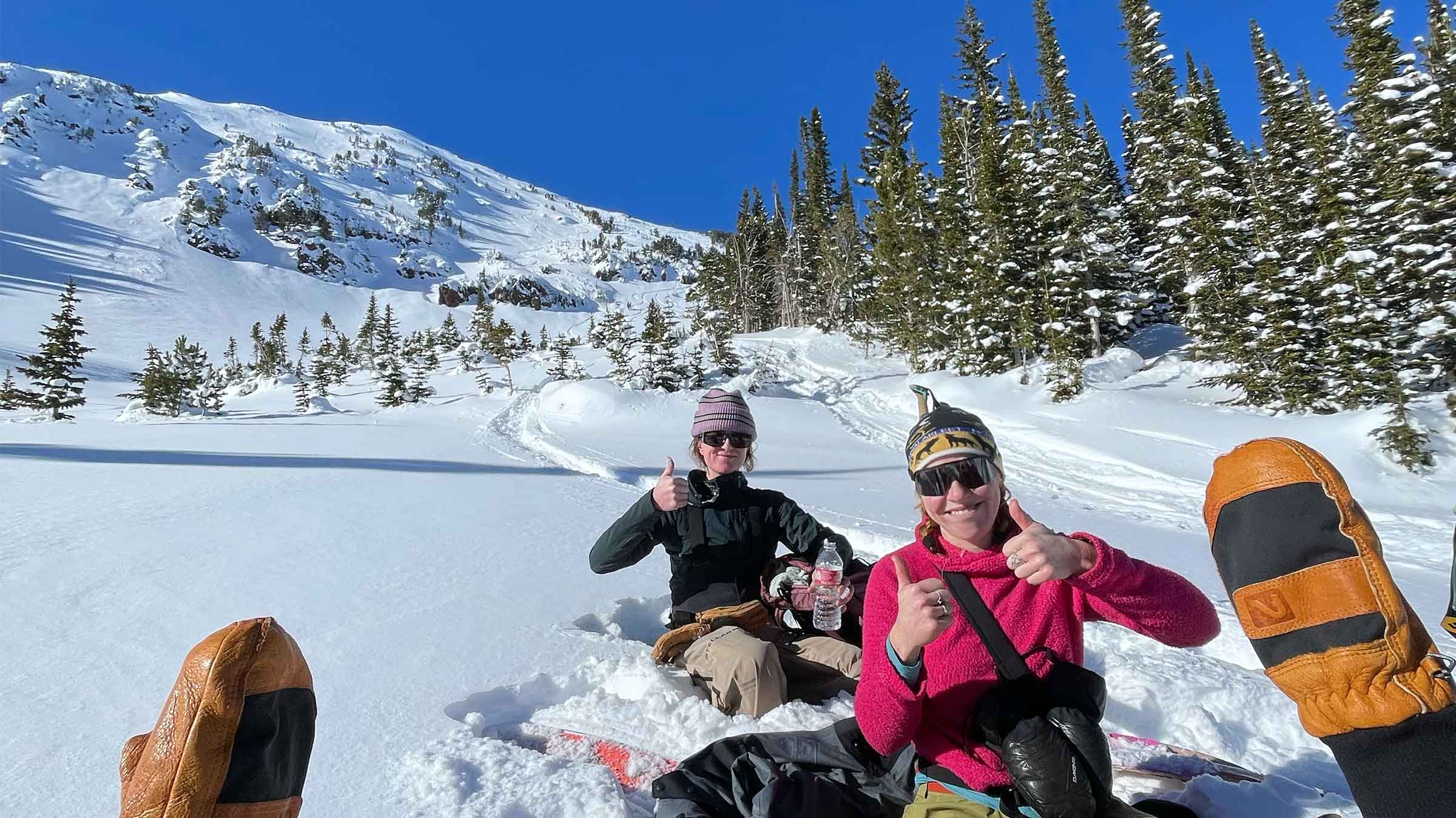 Two women eating lunch while backcountry skiing