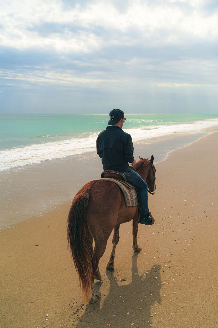 man riding a horse at hutchinson island, home to some of the best beaches in florida