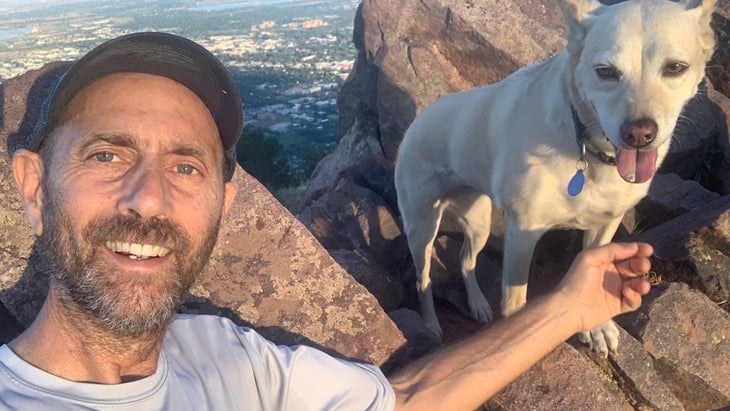 man posing with dog against rocks