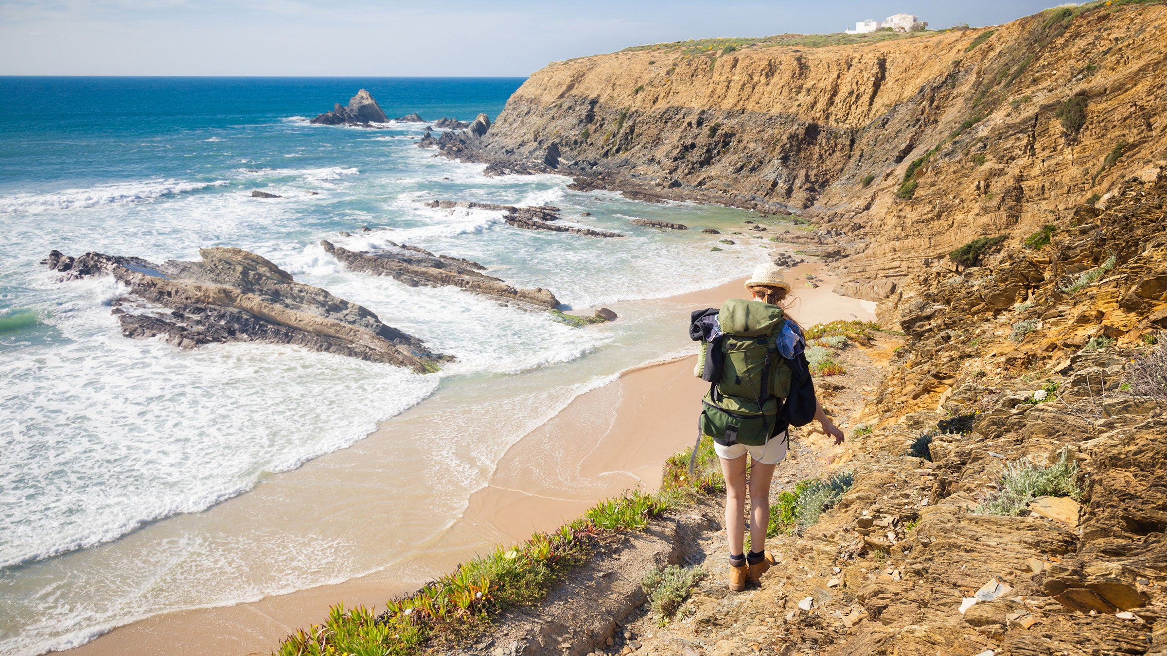 wondering where should I go on vacation? be like this female hiker with rucksack along Palmilhar Portugal trail and take a thru-hike