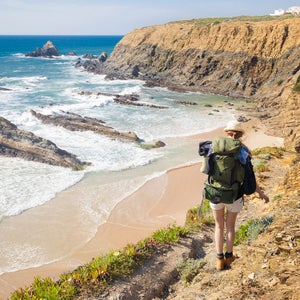 wondering where should I go on vacation? be like this female hiker with rucksack along Palmilhar Portugal trail and take a thru-hike