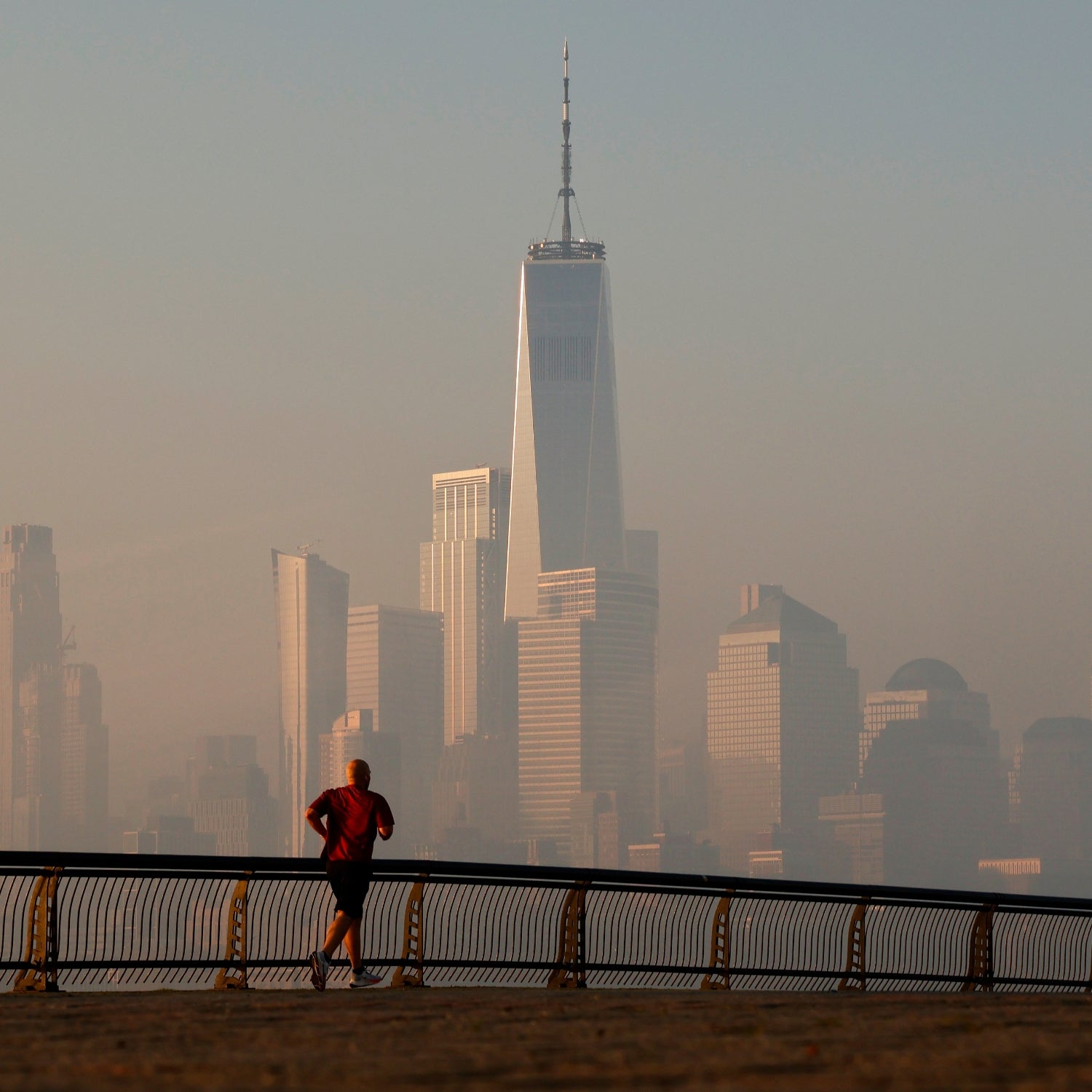 The Manhattan skyline shrouded in air pollution, with a lone runner in the foreground.