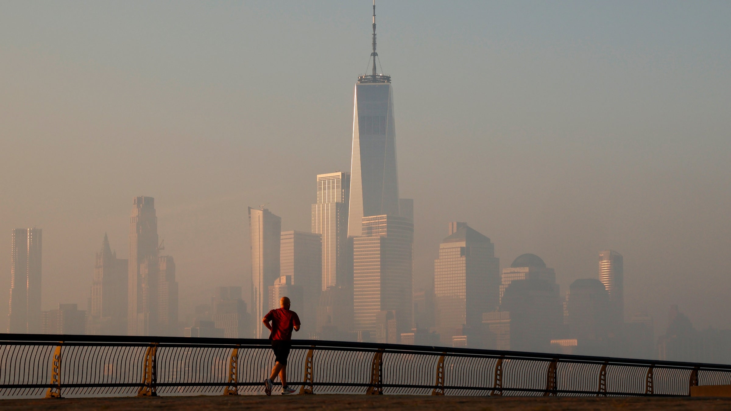 The Manhattan skyline shrouded in air pollution, with a lone runner in the foreground.