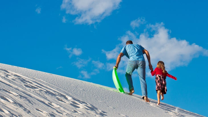 father and daughter sled on Great Sand Dunes