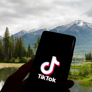 TikTok logo on phone screen against mountain background