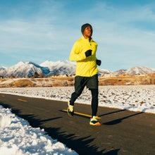 man running on a road in winter in front of snowy mountains