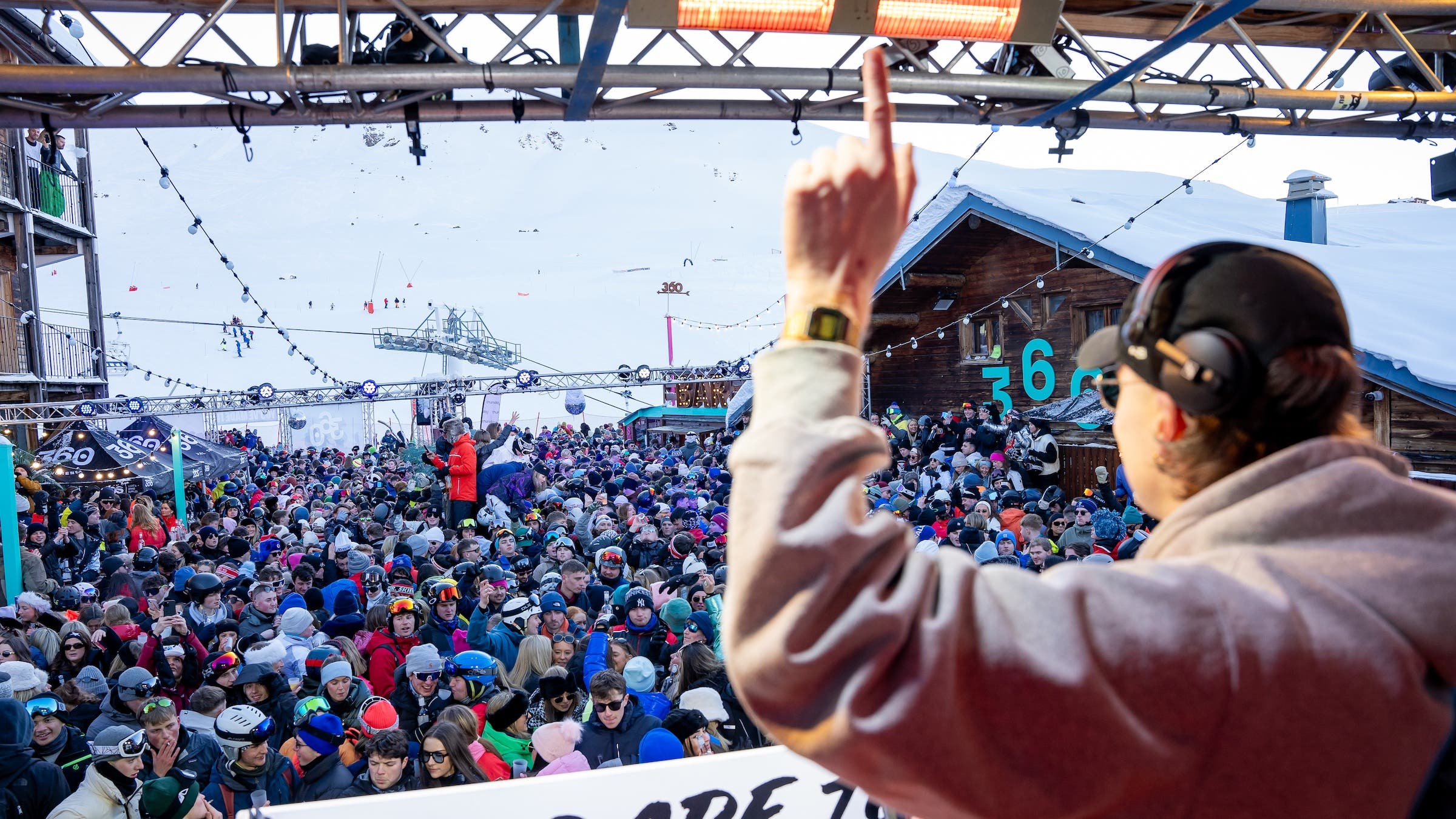 the back of a DJ looking out over an outdoor crowd from a DJ booth