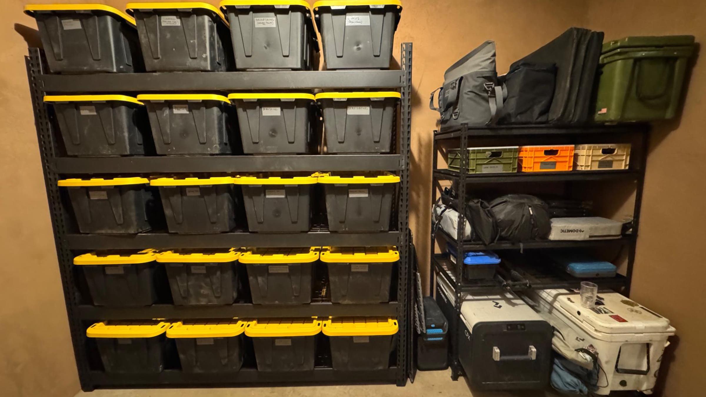 Black heavy duty storage bins stacked on 5-tier shelving unit in garage