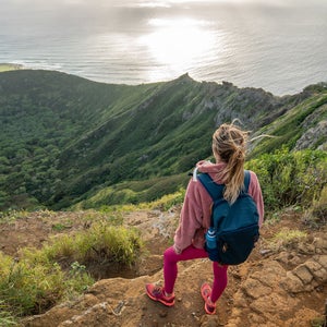 Young woman on mountain top overlooking the ocean, Oahu, Hawaii, USA