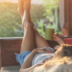 woman lying on outdoor couch with feet in air