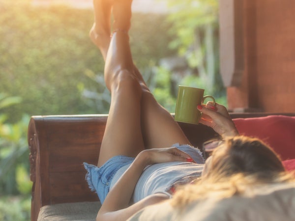 woman lying on outdoor couch with feet in air