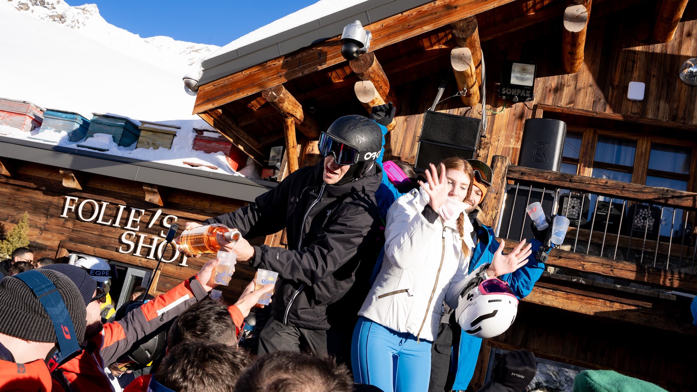 skiers pouring drinks from a bottle at an outdoors bar