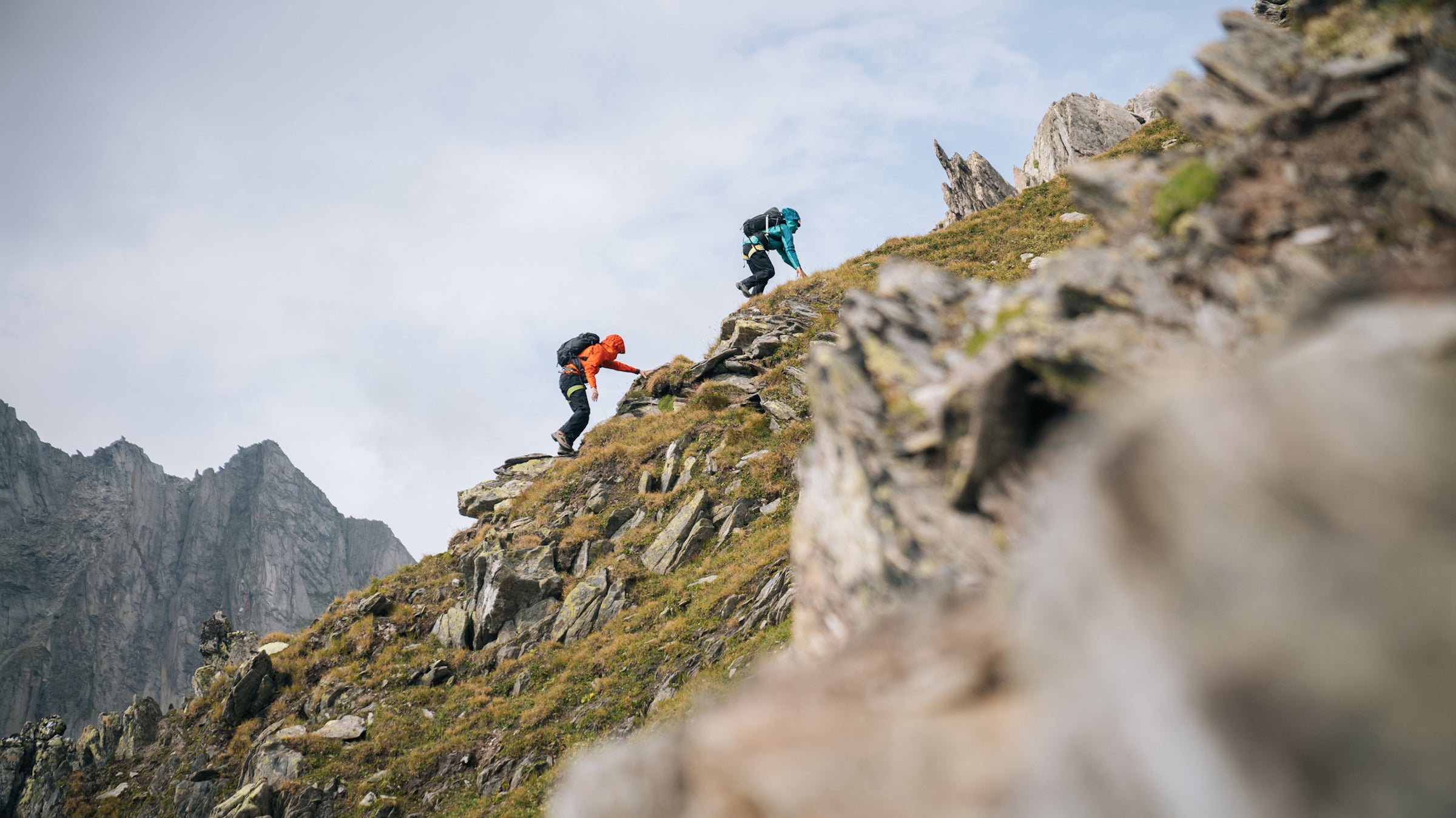 two people scrambling up very steep mountain