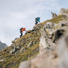 two people scrambling up very steep mountain