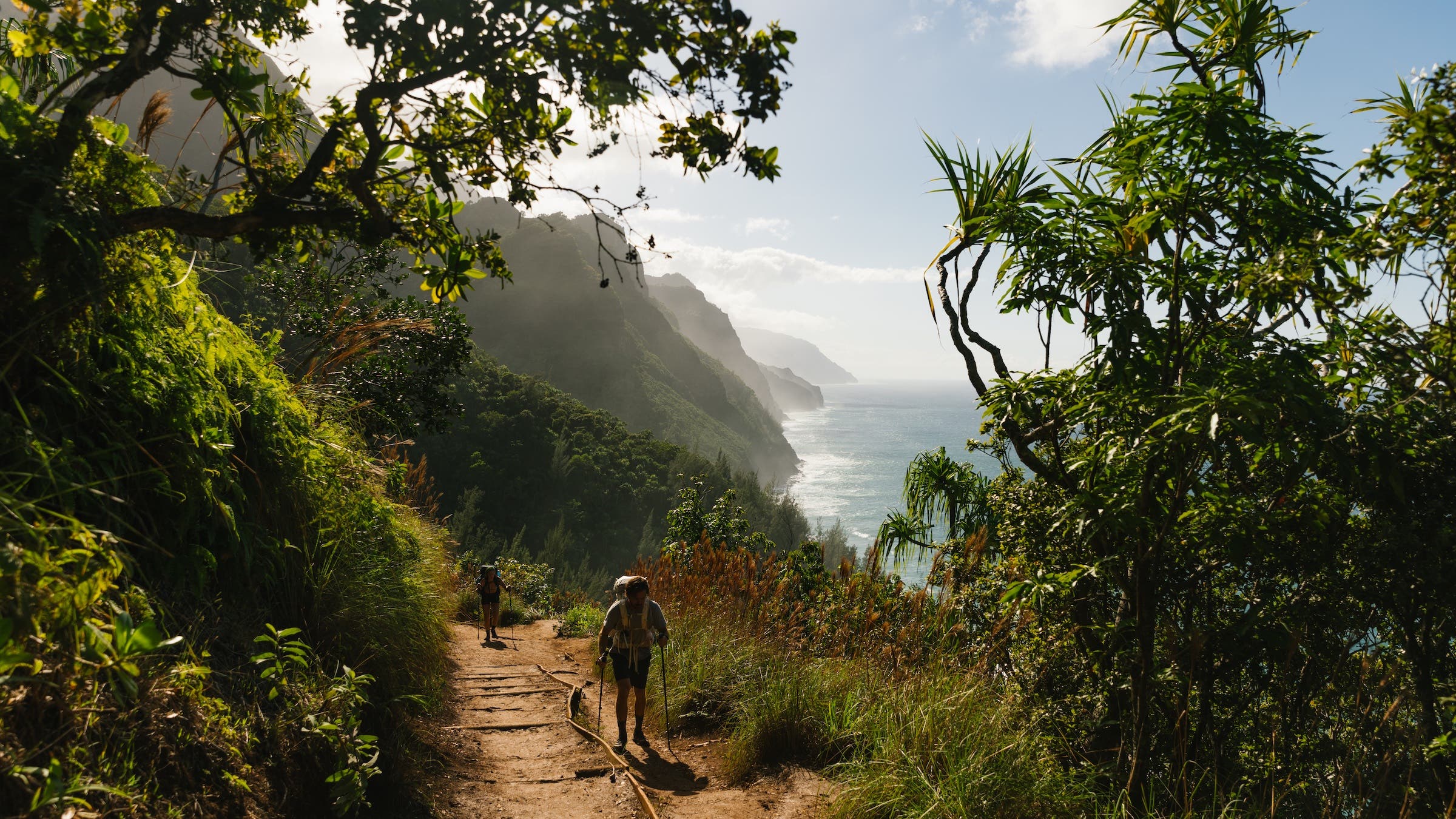 hikers on tropical trail overlooking ocean