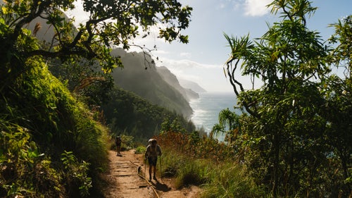 hikers on tropical trail overlooking ocean
