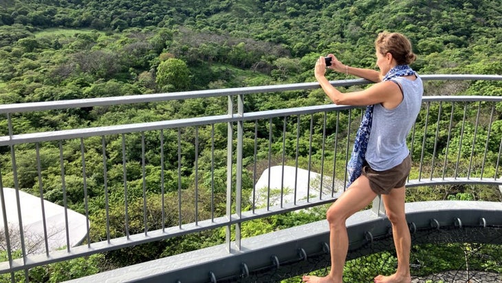 Author Lisa Jhung takes a photo of the jungle with her phone while standing on the deck at Suitree Experience Hotel in Costa Rica.