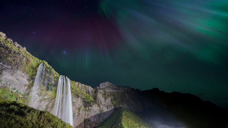 green Northern Lights above a mossy waterfall