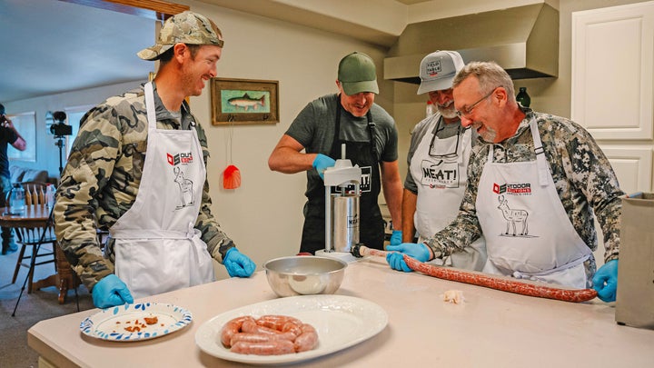 Men standing around a kitchen island making sausage.