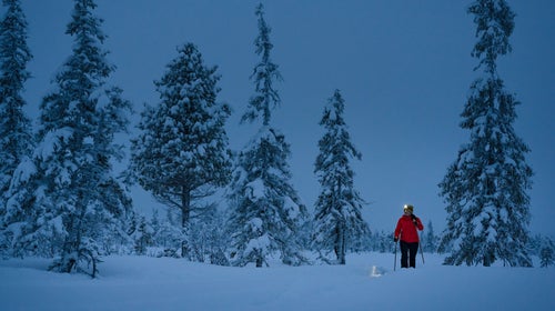 far away hiker in snow with headlamp at dusk