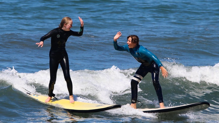 young girls learning to surf manage a high five