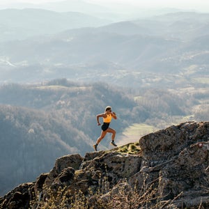 woman trail running up a mountain on rough terrain