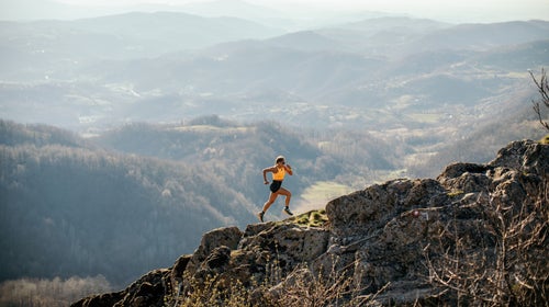 woman trail running up a mountain on rough terrain