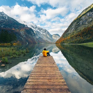A man on a dock at a lake in the Alps.