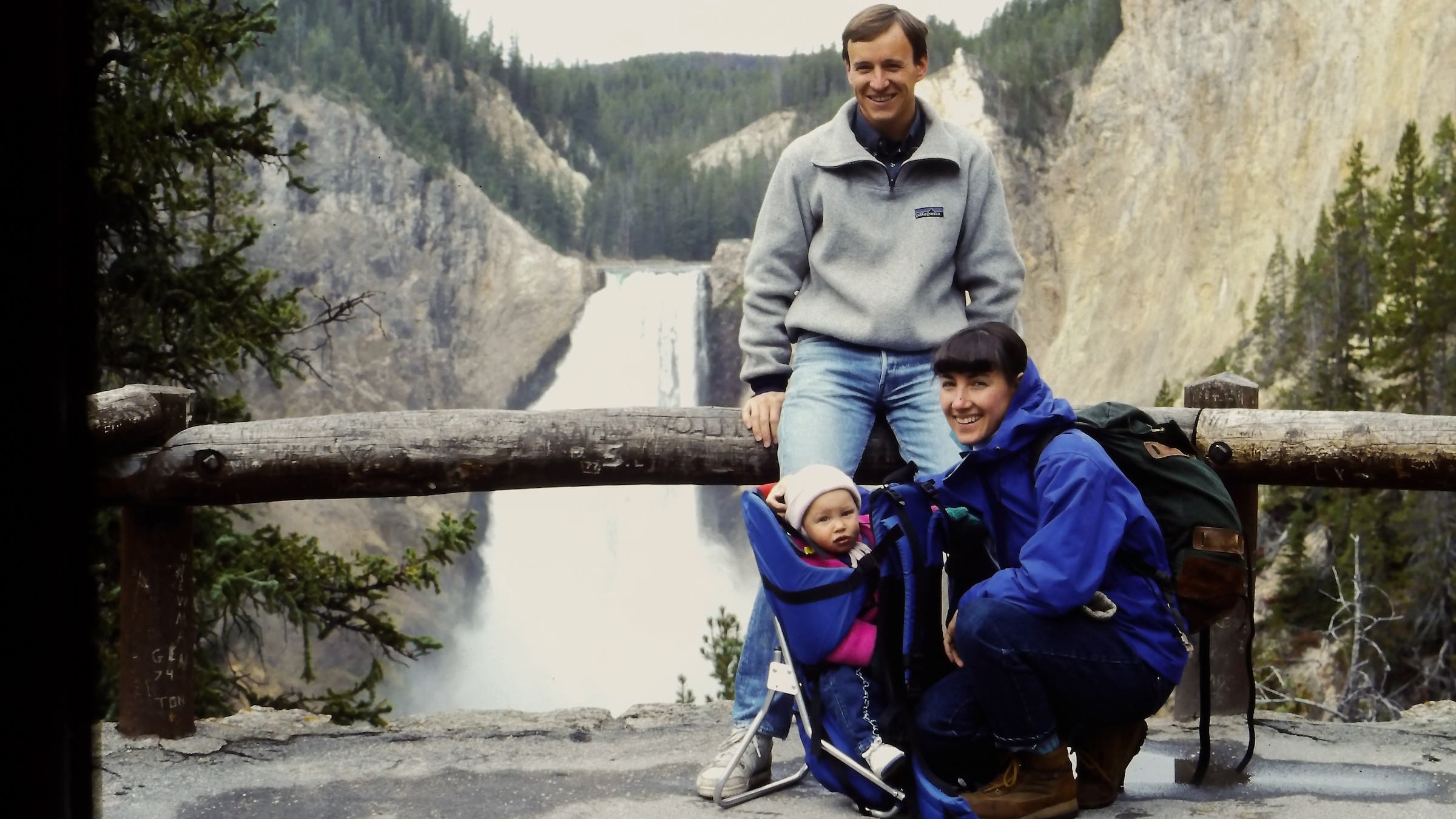 a mom, dad, and baby in front of a waterfall