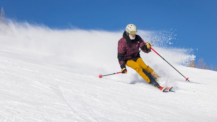 Skier carves down snowy slope on the DPS Pisteworks 79 on a sunny day 