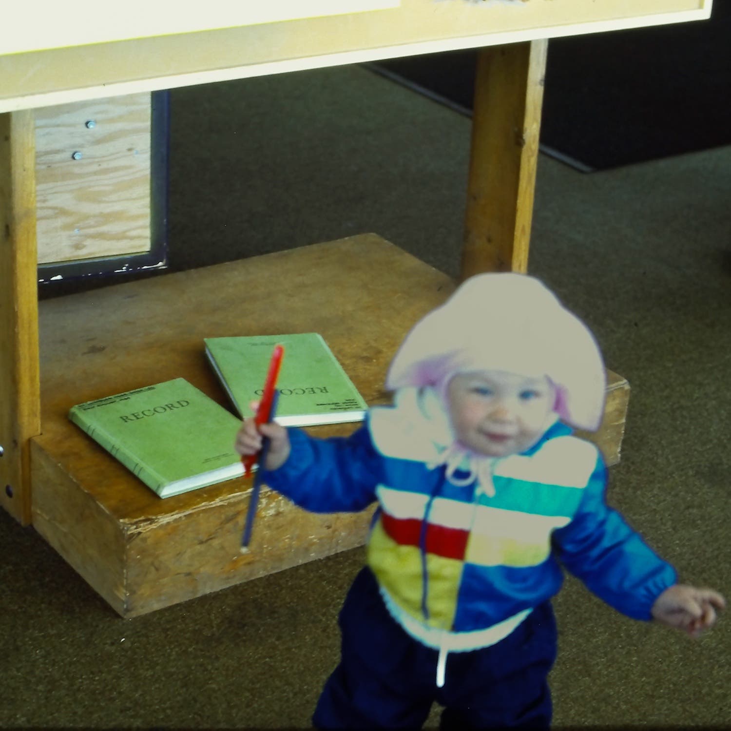 toddler standing in front of green log books