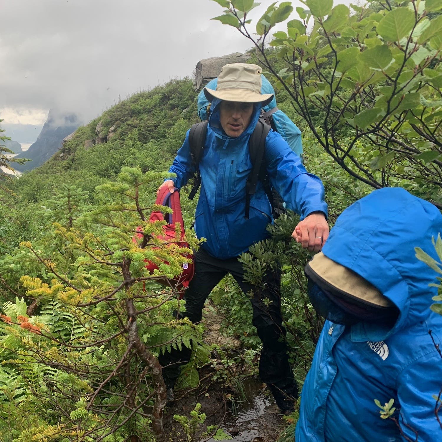 dad and son in blue rain jackets hiking