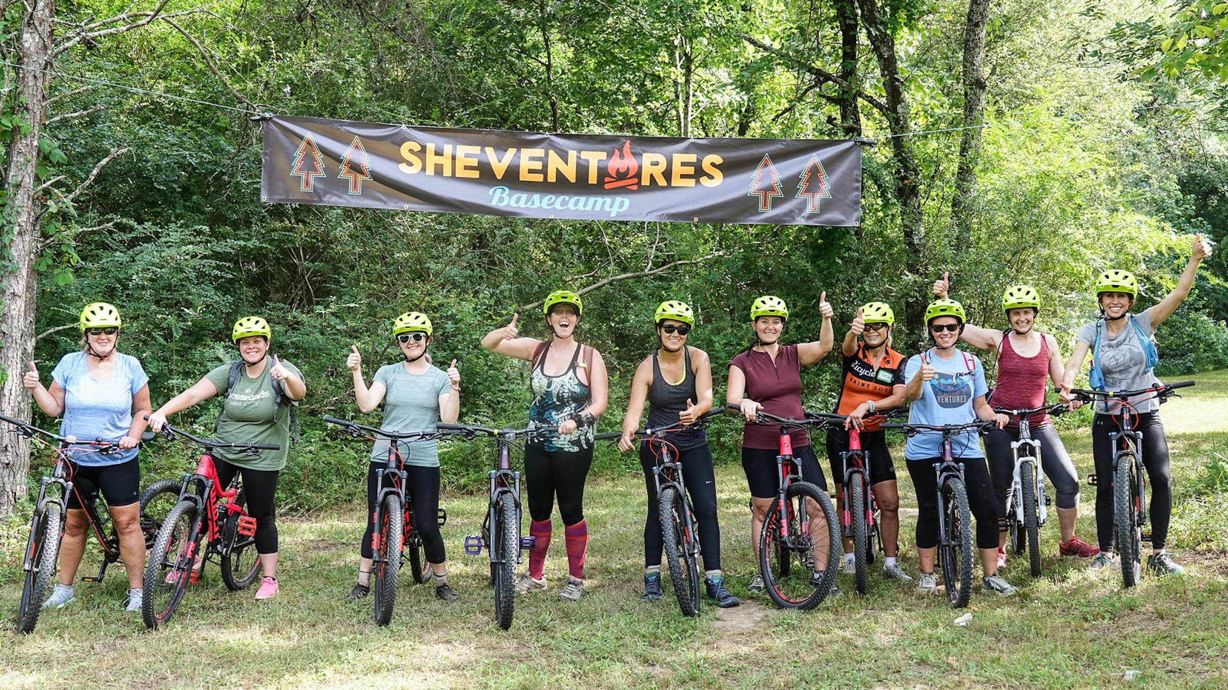 women posing outside next to bikes