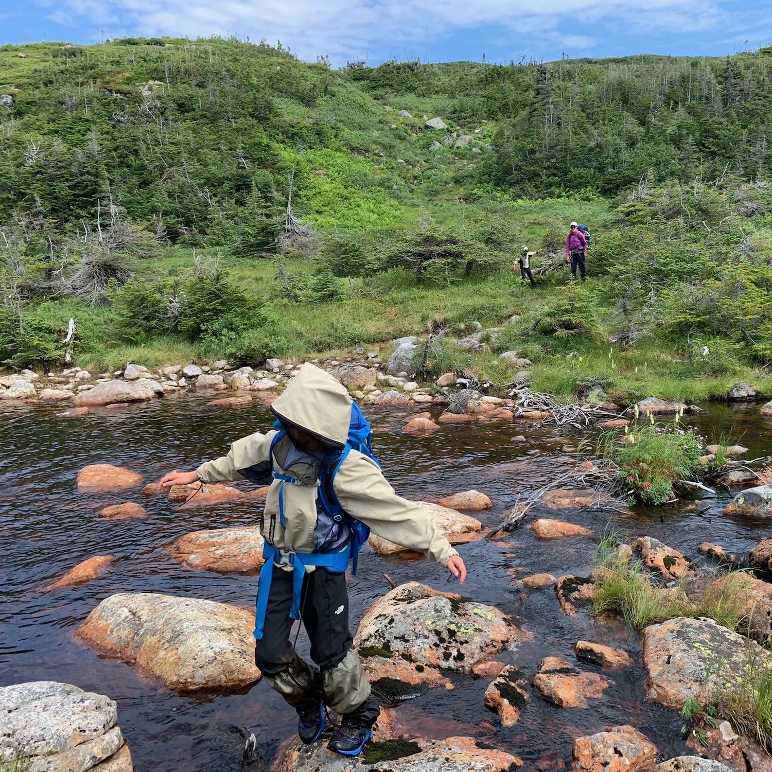 child crossing river on rocks