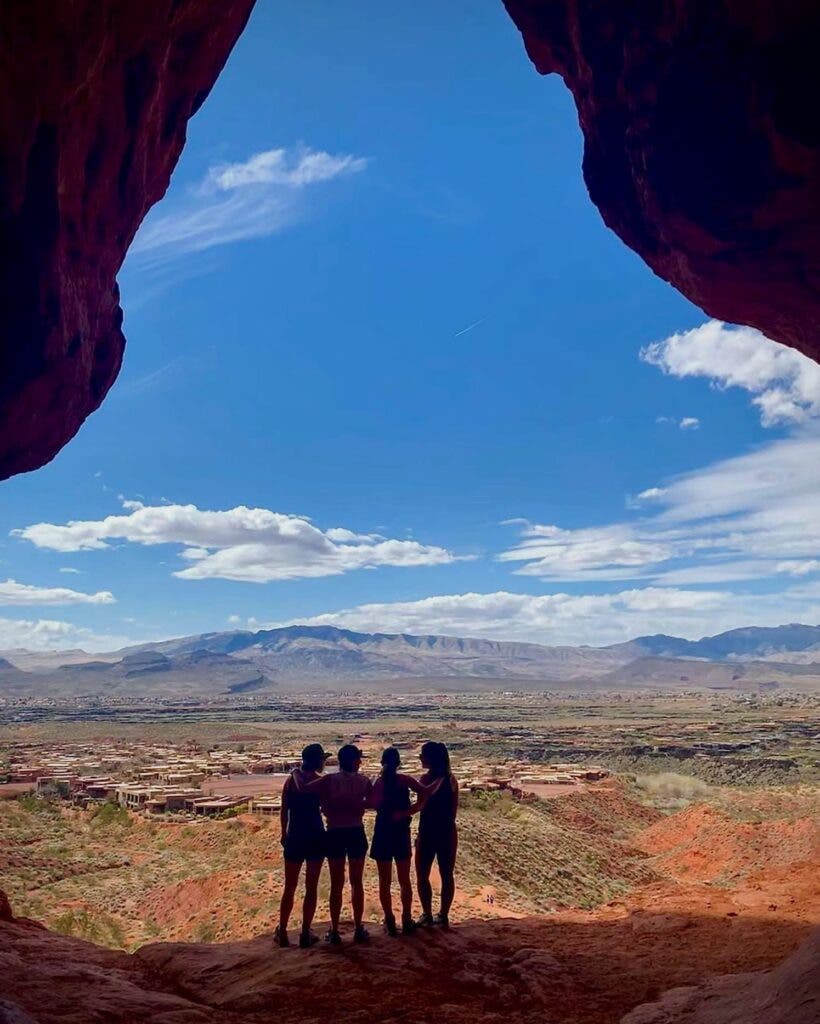 4 silhouettes of women standing in the entrance to a cave